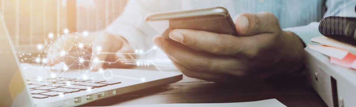 Person Holding Smartphone next to Laptop